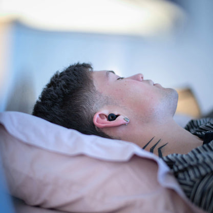 Persona durmiendo llevando unos tapones negros de Mood | Neuromart